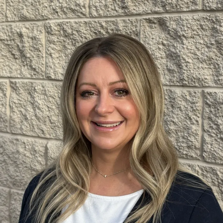 Brittany D., Accounting & Office Coordinator at GCM Construction, wearing a collared shirt in front of a concrete block wall.