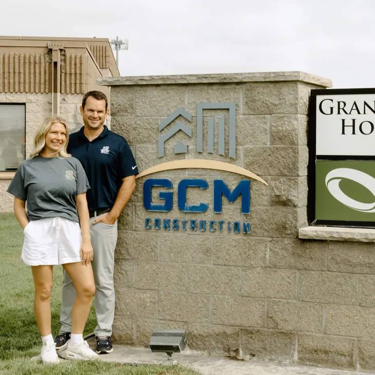 Group photo of GCM Construction owners in Blaine, Minnesota, posing in front of a company sign.