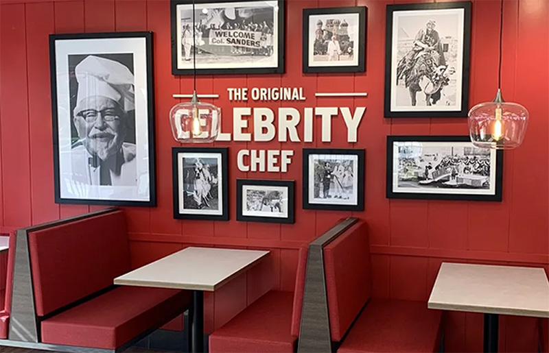 Interior of the Celebrity Chef restaurant featuring red booth seating, brick walls, and a gallery of framed photographs, highlighting a commercial renovation project by GCM Construction.