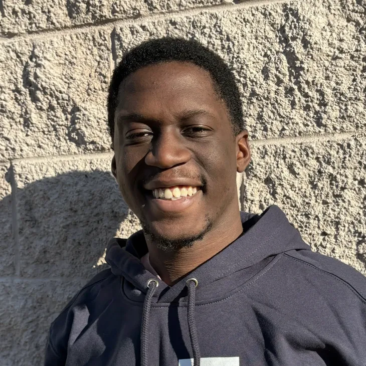 Kyle O., Service Technician at GCM Construction, wearing a collared shirt in front of a concrete block wall.