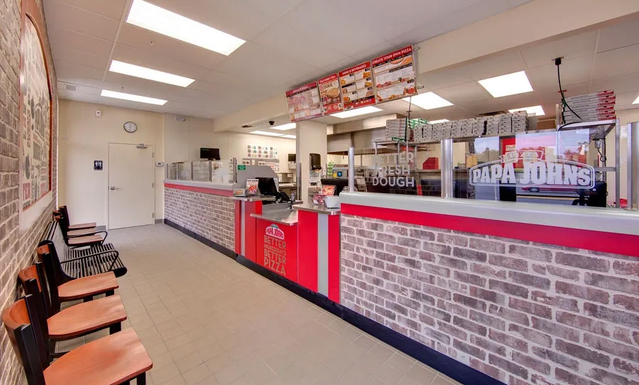 Interior of the Papa John’s restaurant in Maple Grove, Minnesota, featuring the customer service counter, branded menu displays, and a functional food preparation area built by GCM Construction.