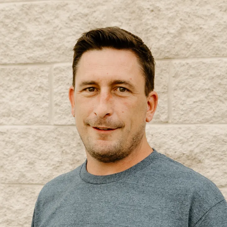 Zach L., Site Superintendent at GCM Construction, wearing a collared shirt in front of a concrete block wall.